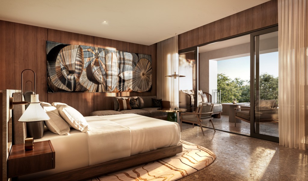 Waldorf Astoria Costa Rica Punta Cacique Guest room, bed, side table and lamp, couch and small table with chair, rug under bed, art piece on the wall, wood wall panels, open balcony patio doors with couch, chairs and table with covered candle