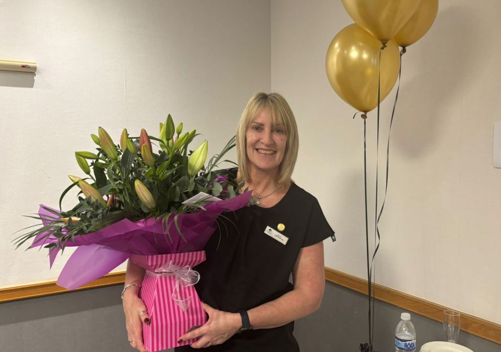 Denise Beadle, DoubleTree by Hilton Swindon - Hilton 2024 CEO Light &amp; Warmth Award Winner, Denise holding flowers and standing next to balloons