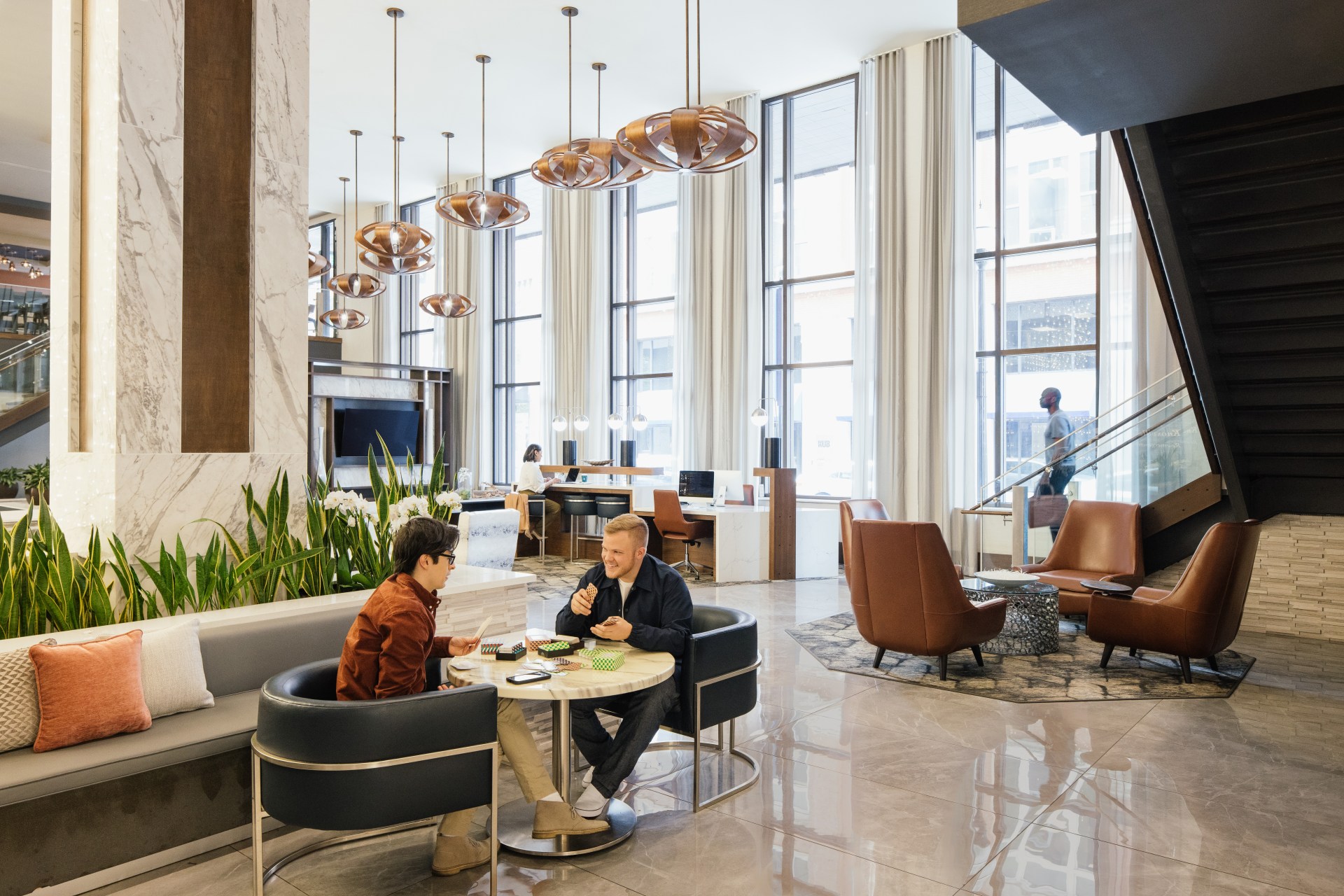 Embassy Brand, Lifestyle, Lobby, sitting area, two people playing cards, leather chairs, work station, potted plants