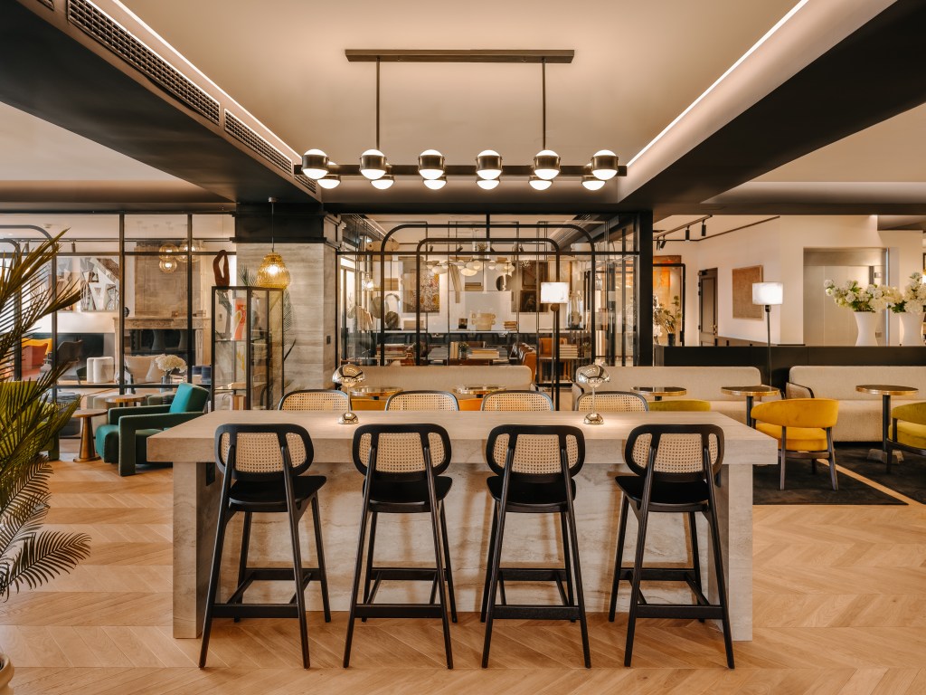 Marty Hotel Bordeaux Tapestry Collection by Hilton,  Lobby, black bar stools, yellow chairs, green chairs, wood floor, marble bar, gold bistro tables, white lounge seating