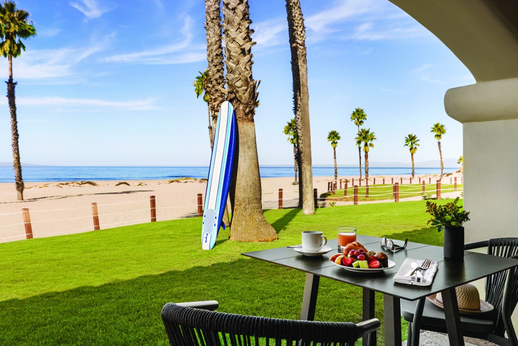 Zachari Dunes on Mandalay Beach, Curio Collection by Hilton - King Deluxe Suite, Ocean Front, table and chairs with a breakfast plate and drinks facing beach and oceah, surf board leaning up again a tree