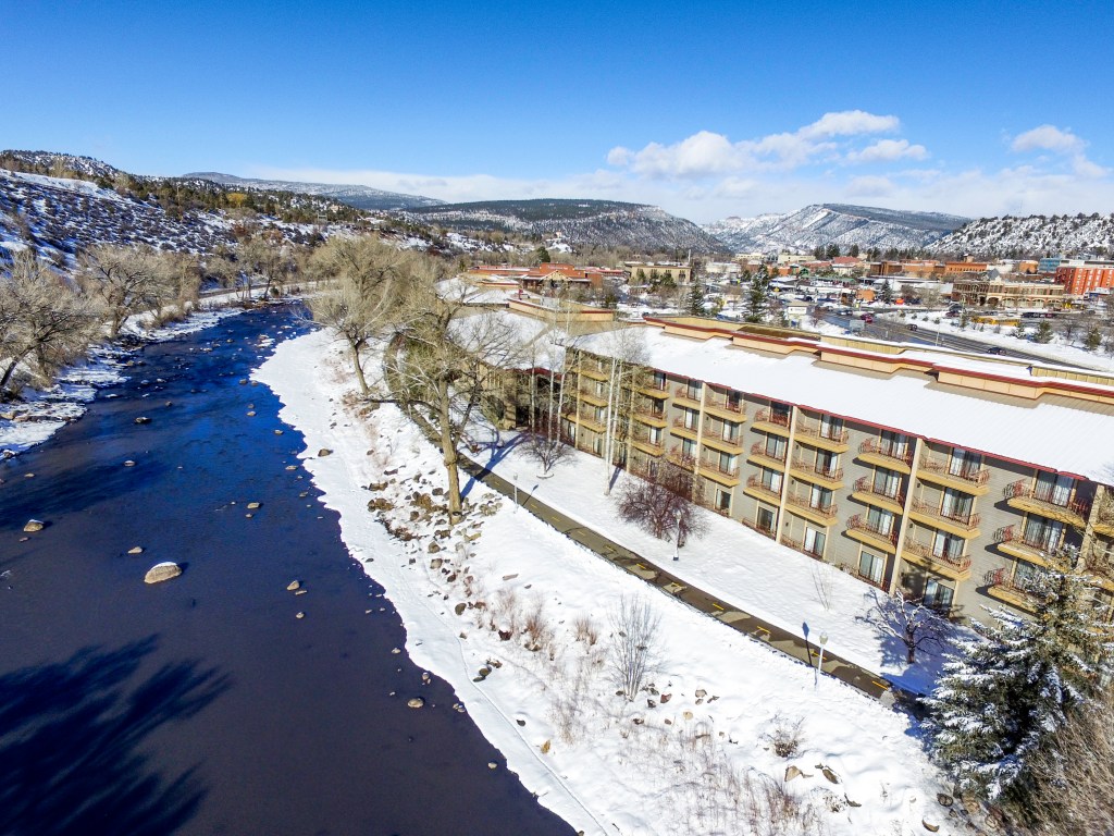 An aerial image of the DoubleTree by Hilton Hotel Durango location that features a large body of water, snow covered ground, and mountains in the background.