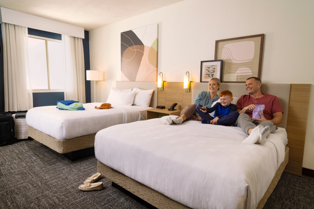 Spark by Hilton - Guest Room with Family on bed watching tv