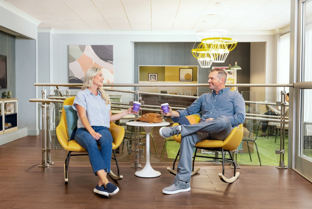 Spark by Hilton - Lobby Area Seating, two people at table sitting in yellow rocking chairs over coffee