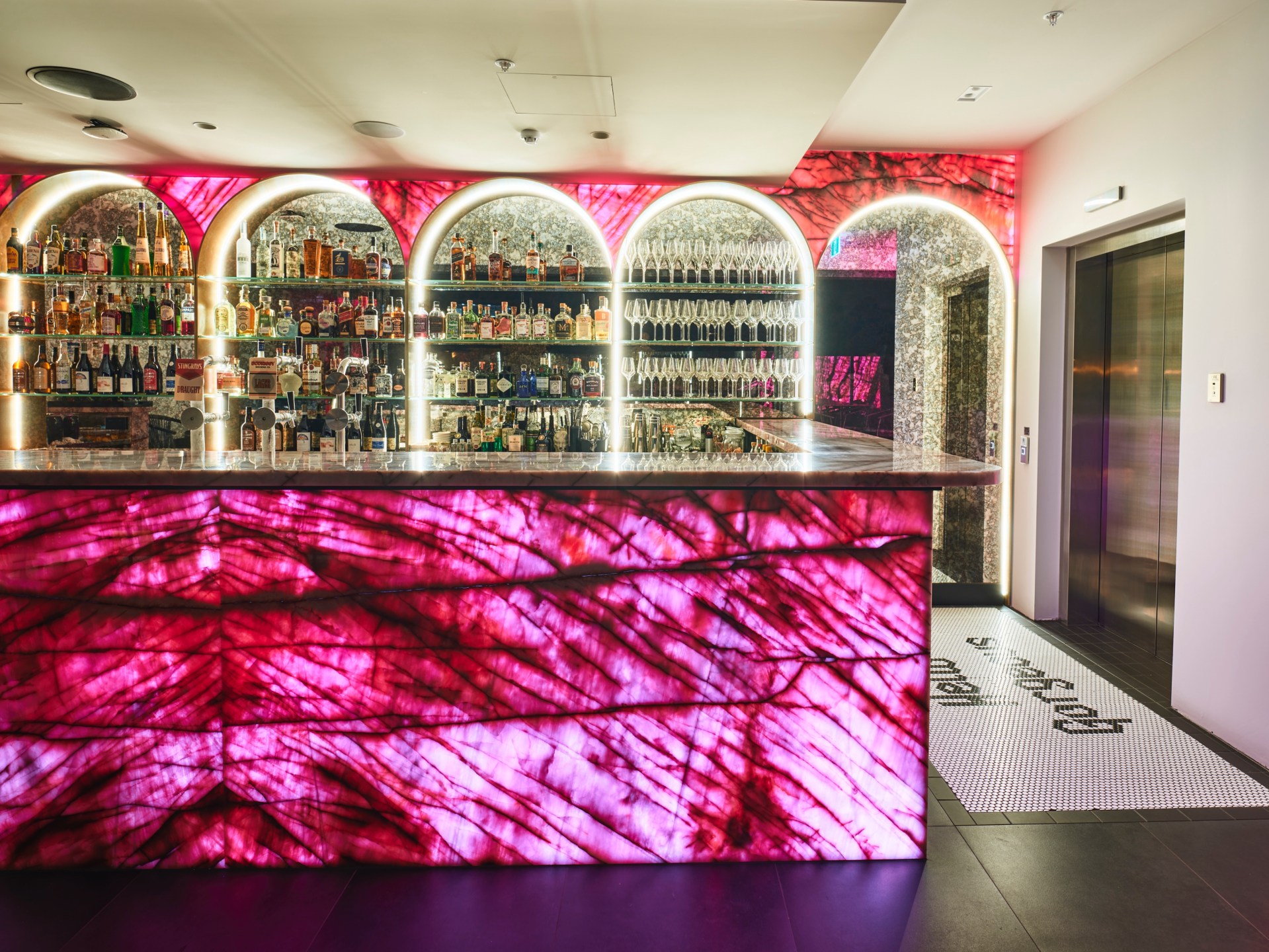 The Motley Hotel Richmond, Tapestry Collection by Hilton, Bar, pink stained glass, tiled entryway, marble counter, stemmed wine glasses, liquors, draft beer, black tiled floor