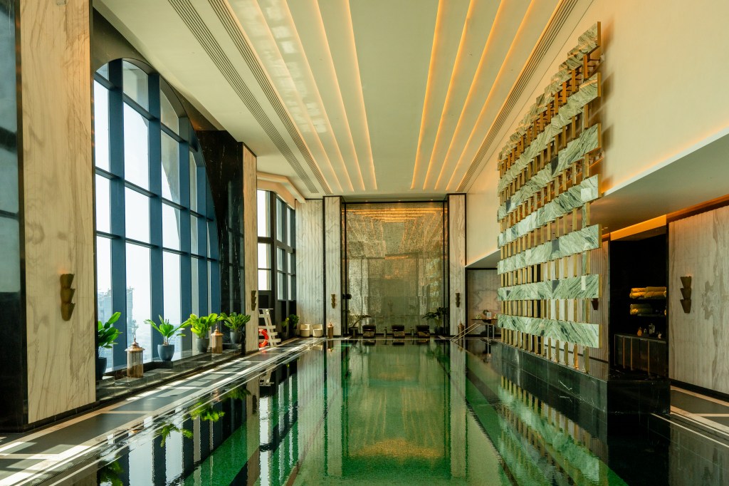 Waldorf Astoria Doha West Bay, Indoor Pool, decorative wall, potted plants, sconce light fixtures, arched window wall