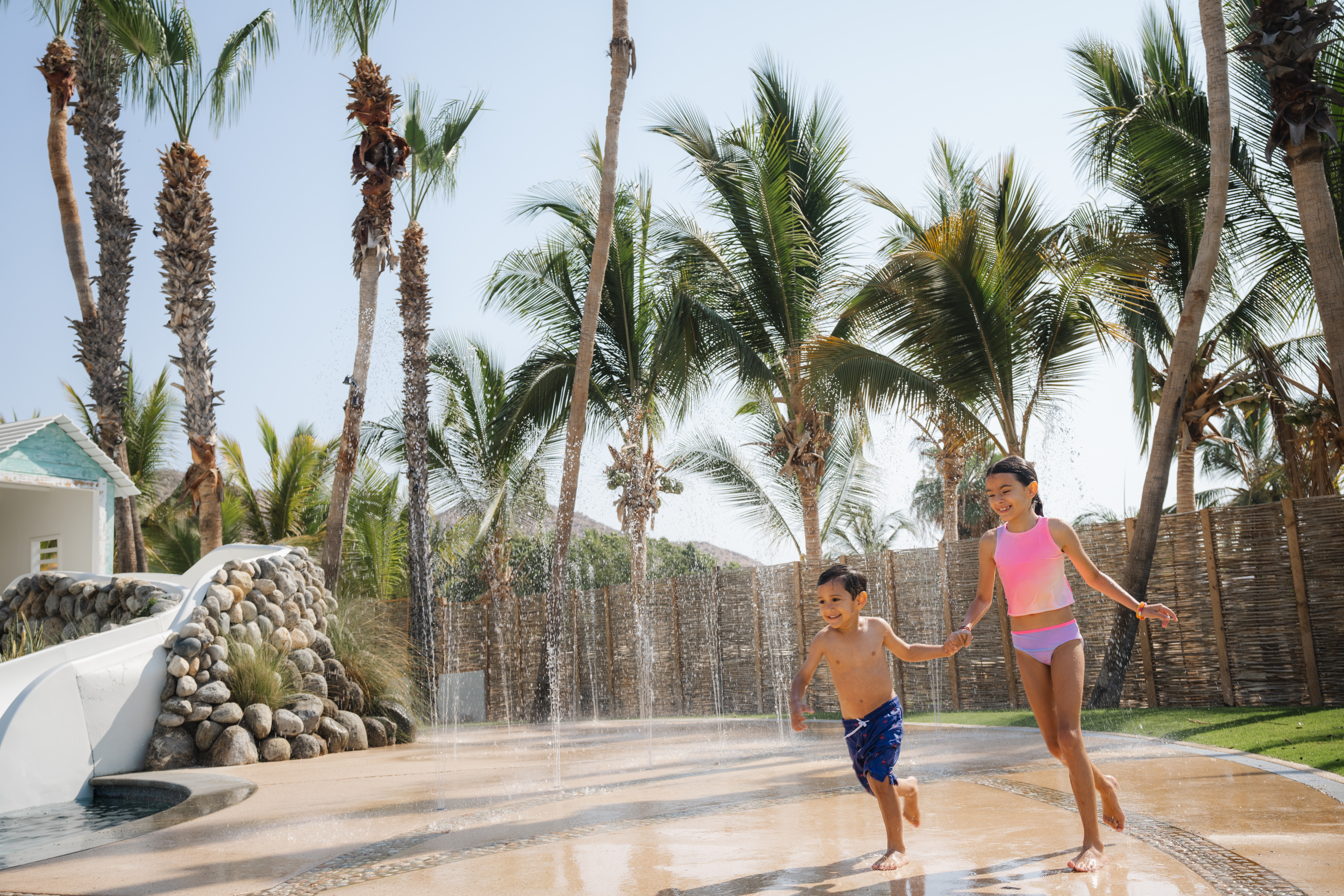 Hilton Los Cabos, Splash Zone, two kids playing on a splash pad, water foundation, palm trees