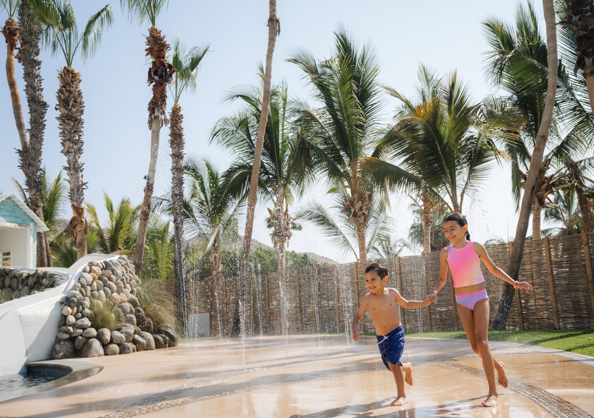 Hilton Los Cabos, Splash Zone, two kids playing on a splash pad, water foundation, palm trees