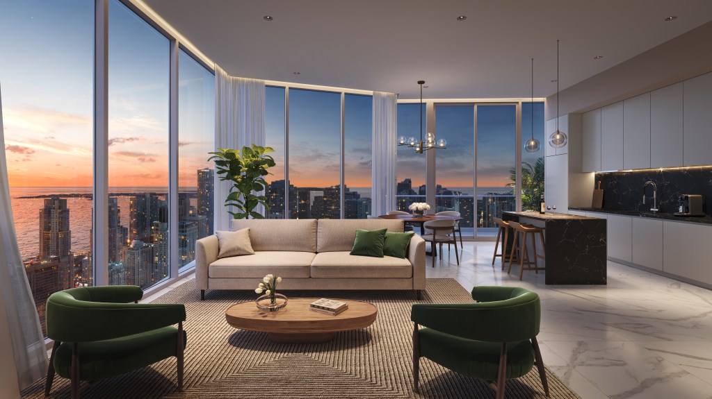 Modern open-concept living and kitchen area with city sunset views, beige sofa, green chairs, and a black marble island.