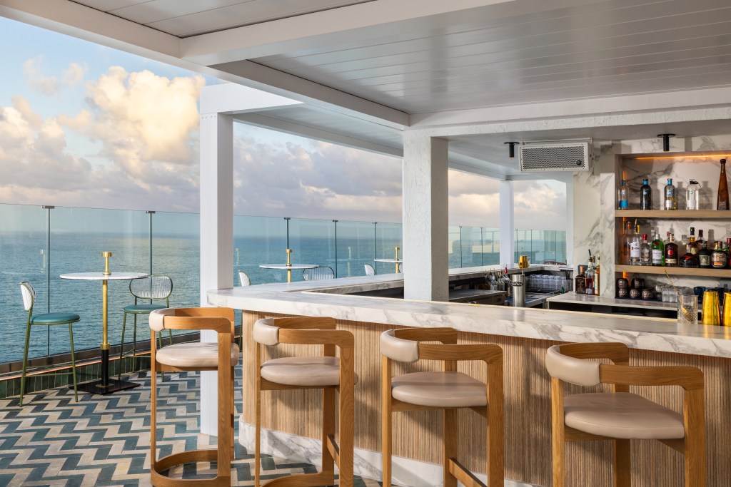 Beach House Fort Lauderdale, a Hilton Resort - Nubé - roof top bar area with view of the ocean, glass barriers around the perimeter, high tables and chairs