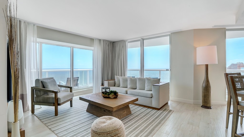 Beach House Fort Lauderdale, a Hilton Resort - Oceanfront One Bedroom Suite - Living Room, couch and chair and coffee table in the middle of a room, lamp and high chairs off to the side