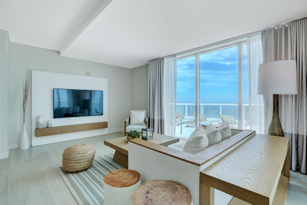 Beach House Fort Lauderdale, a Hilton Resort - Oceanfront Two Bedroom Suite, living room area with couch, coffee table, chairs, TV and a balcony with lounge chairs