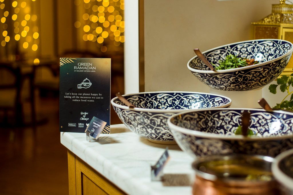 Serving bowls with a sign explaining Green Ramadan and encouraging reduction of food waste