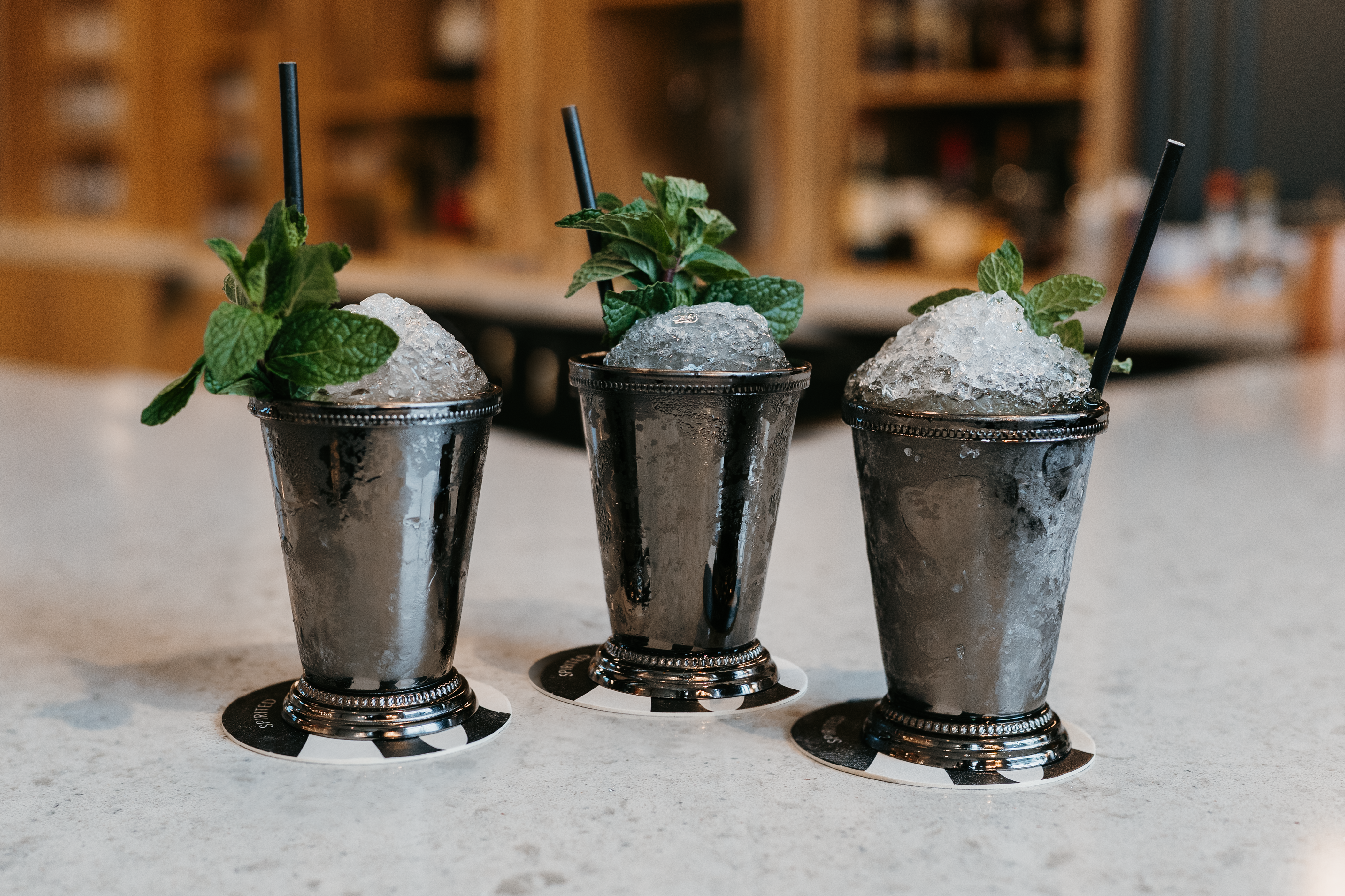 Tempo by Hilton, three Cocktails, pebble ice, mint garnish, straws, black and white drink coasters