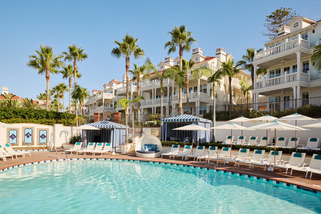 The Beach Village at Hotel Del Coronado, LXR Hotels & Resorts, view of Pool area with lounge chairs and cabanas and umbrellas and palm trees and water fountains