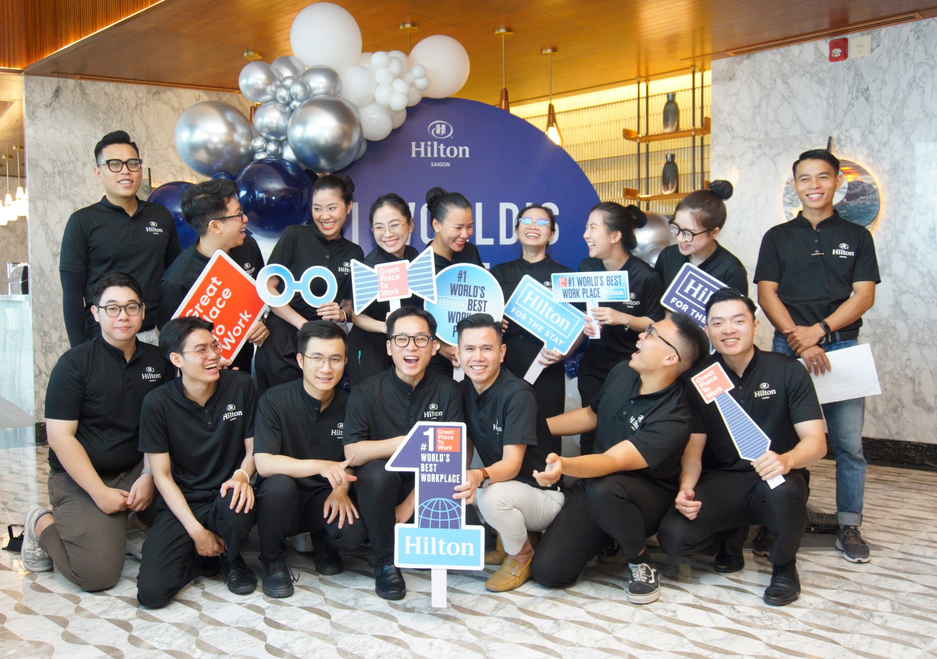 Hilton Named #1 Best Workplace in Vietnam - Hilton Saigon - group photo of team members with Great Place to Work signs posing in front of a backdrop with balloons