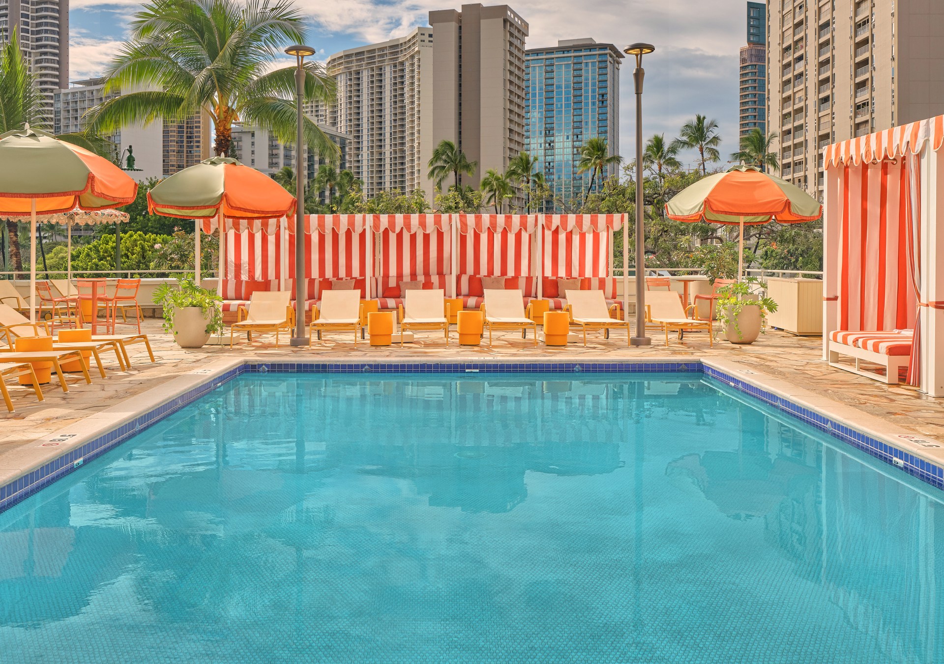The Ambassador Hotel of Waikiki, Tapestry Collection by Hilton - Pool - Credit - Michael Clifford, pool area with lounge chairs and red and white stripe cabanas