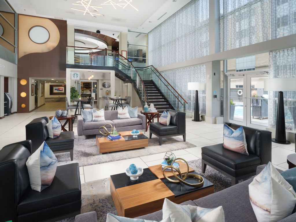 DoubleTree by Hilton Chattanooga Downtown Lobby with lounge seating and coffee tables at the bottom of stairs with tall floor lamps and high top tables