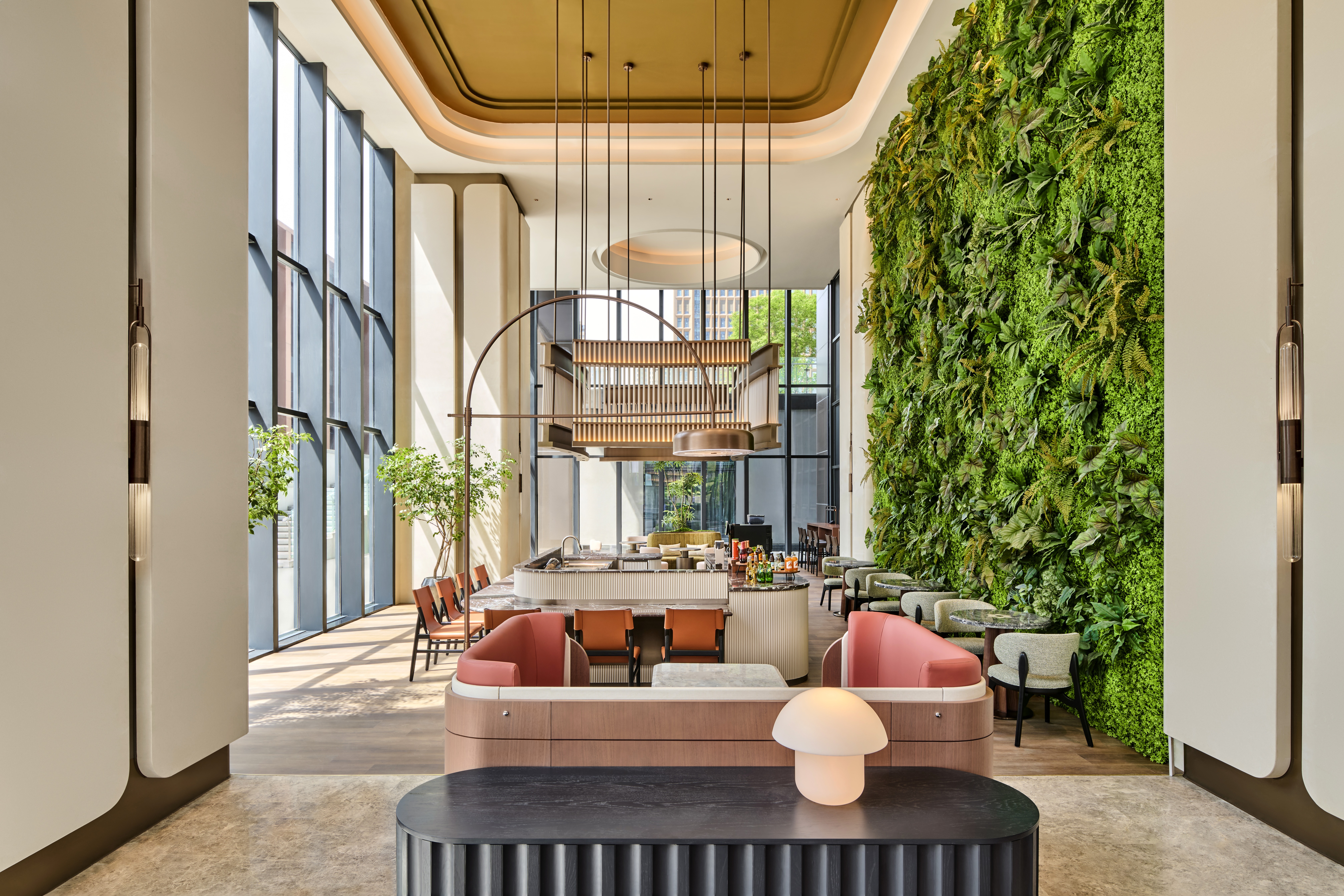Hilton Garden Inn Chongqing Yubei Central Park Lobby with tables and chair seating area around a cafe bar with a living plant wall on one side of the room and floor to ceiling windows on the opposite side of the room