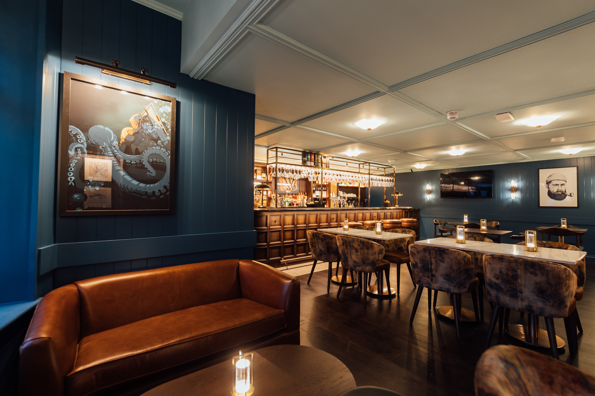 Bar with navy blue walls, variety of seating, wood accents and nautical themed artwork at The Marcus Portrush, Tapestry Collection by Hilton - Bar