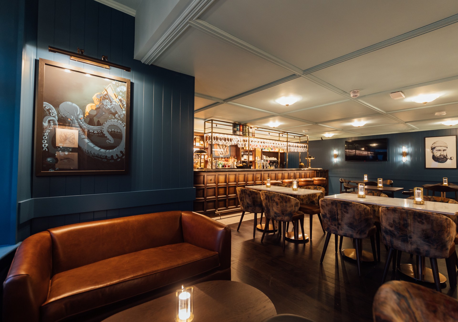Bar with navy blue walls, variety of seating, wood accents and nautical themed artwork at The Marcus Portrush, Tapestry Collection by Hilton - Bar