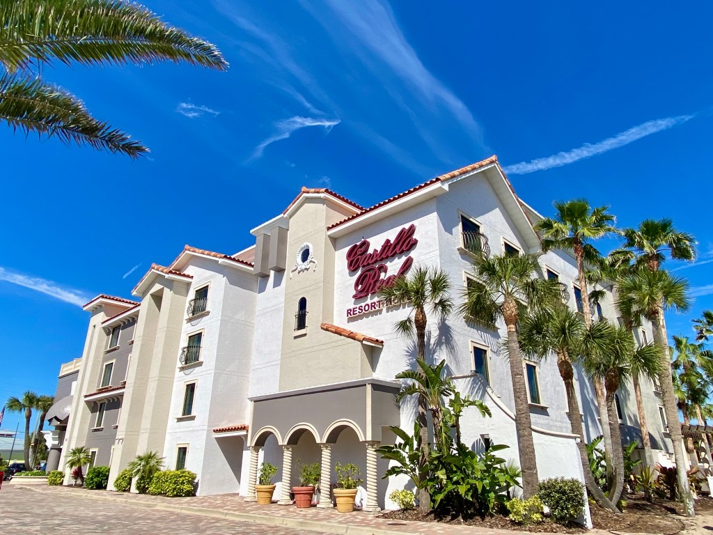 Castillo Real St. Augustine Beach, Tapestry Collection by Hilton - exterior of hotel during the day, white building with blue sky and palm trees