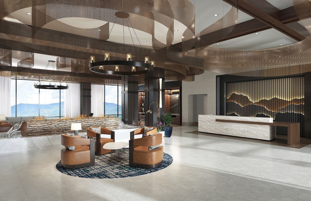 Embassy Suites by Hilton Pigeon Forge Resort, Lobby with leather seat sitting area on a circular area rug with a table and lamps with a black round chandelier hanging above next to a log shaped indoor water fountain and log shaped fire place and a reception desk with a backdrop displaying sillouettes of mountains
