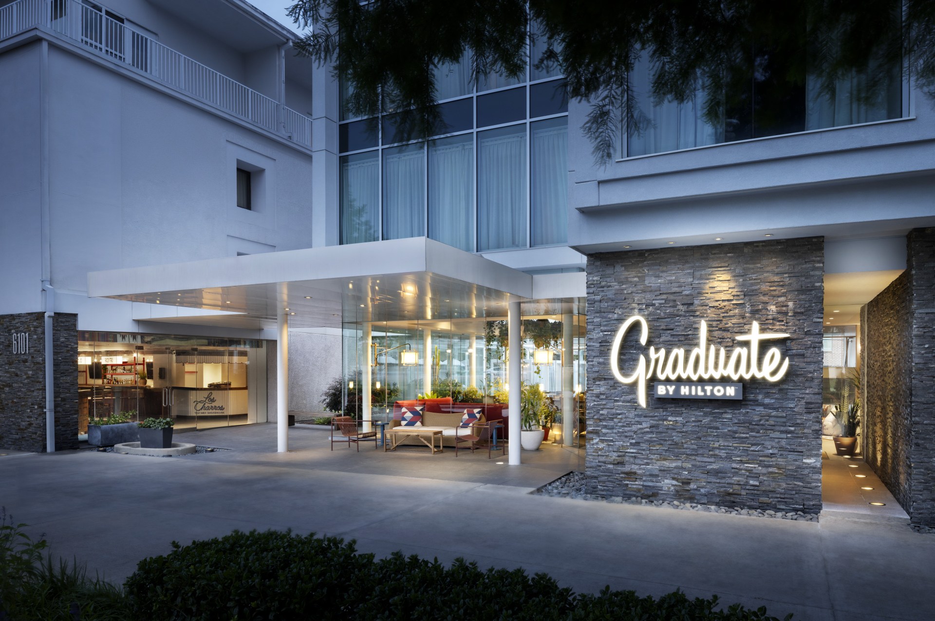 Graduate by Hilton Dallas Exterior with an outdoor seating area surrounded by potted plants and outdoor lighting