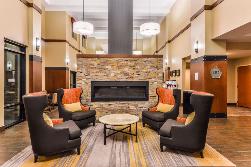 Hampton Inn &amp; Suites Boulder-North lobby with four large chairs around a table in front of a fireplace