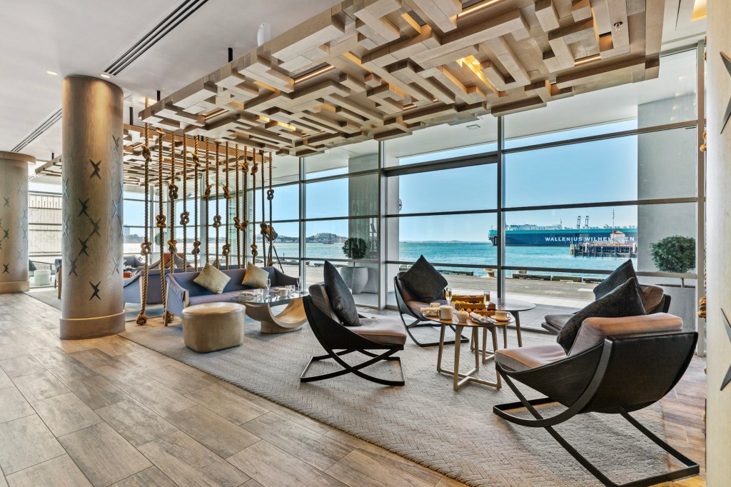 Contemporary lounge area at Hilton Auckland’s Bellini Bar featuring nautical-inspired design, rope accents, and panoramic harbor views through floor-to-ceiling windows. Bellini Bar, Hilton Auckland. Hilton