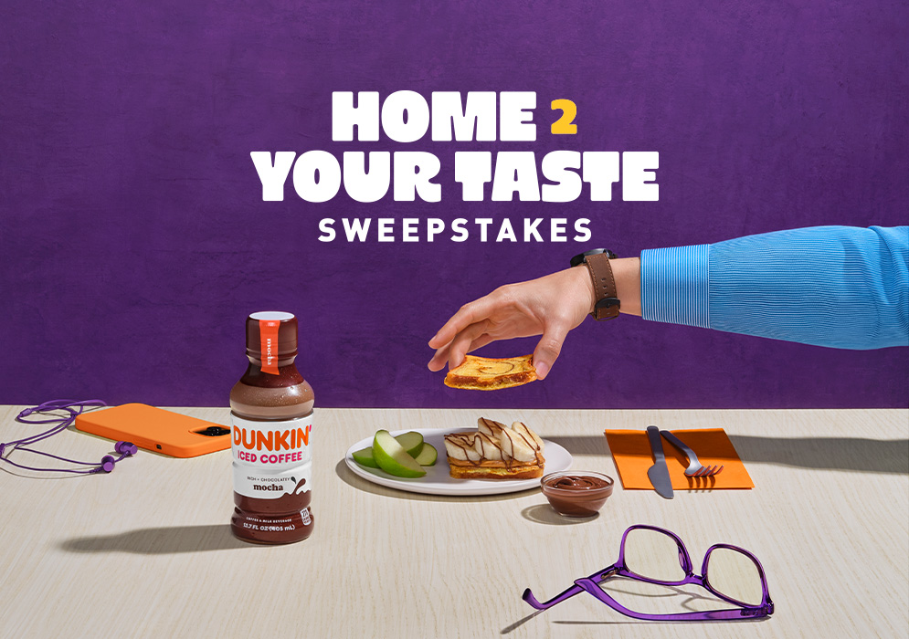 Home2 Your Taste Sweepstakes logo above a breakfast table with Home2 Suites by Hilton breakfast sandwich, cutlery, Dunkin’ Iced Coffee, a cellphone and glasses