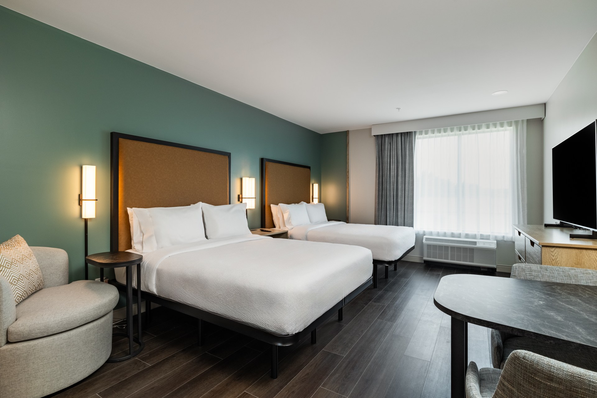 LivSmart Studios by Hilton Tullahoma - Guest Room Beds - two beds with white bedding, teal wall, table and chairs, seating area, television and windows