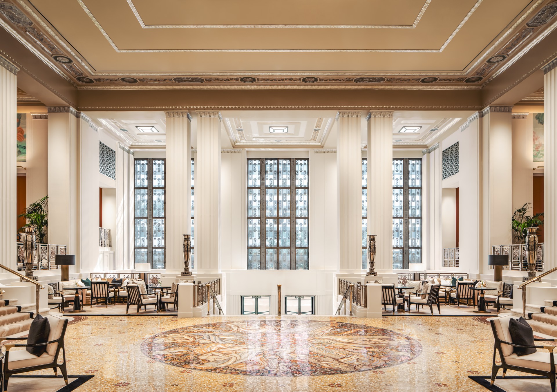 Waldorf Astoria New York - Park Avenue Lobby with lounge seating looking over white columns surrounding the iconic 148,000 hand-cut tile “Wheel of Life” mosaic by Louis Rigal