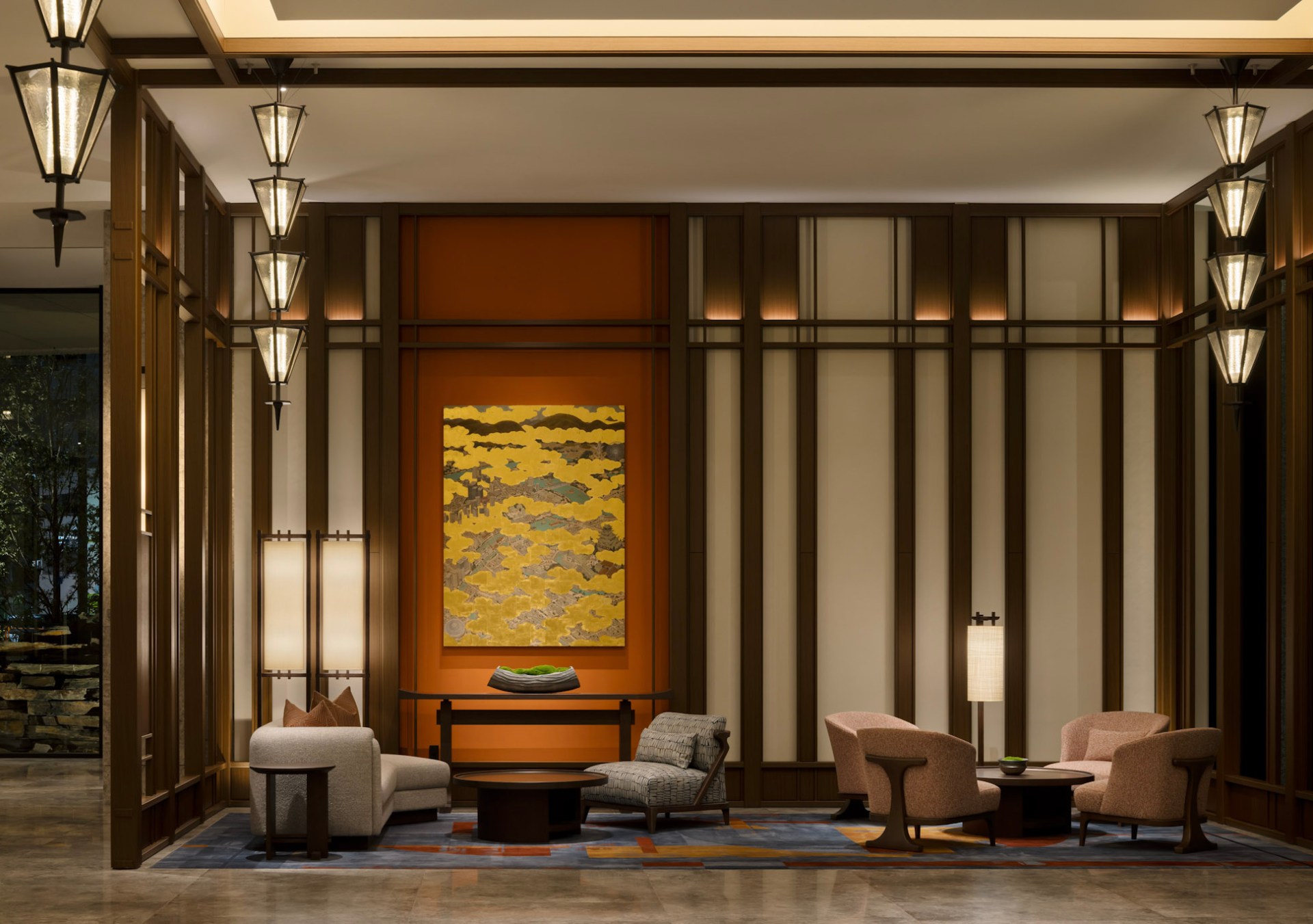 Contemporary hotel lounge with comfortable seating, vertical wood paneling, and a golden-hued abstract painting. | Waldorf Astoria Osaka - Grand Entrance - Lobby | Hilton