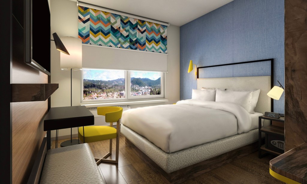 Bright bedroom with queen bed and colorful window shades.