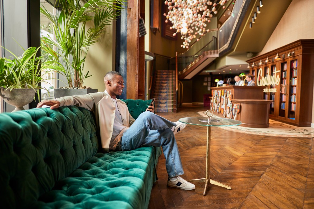 Graduate by Hilton Cambridge Lobby, man sitting on green sofa in lobby