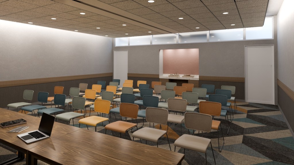 A meeting room with multi colored chairs set up facing the front of the room