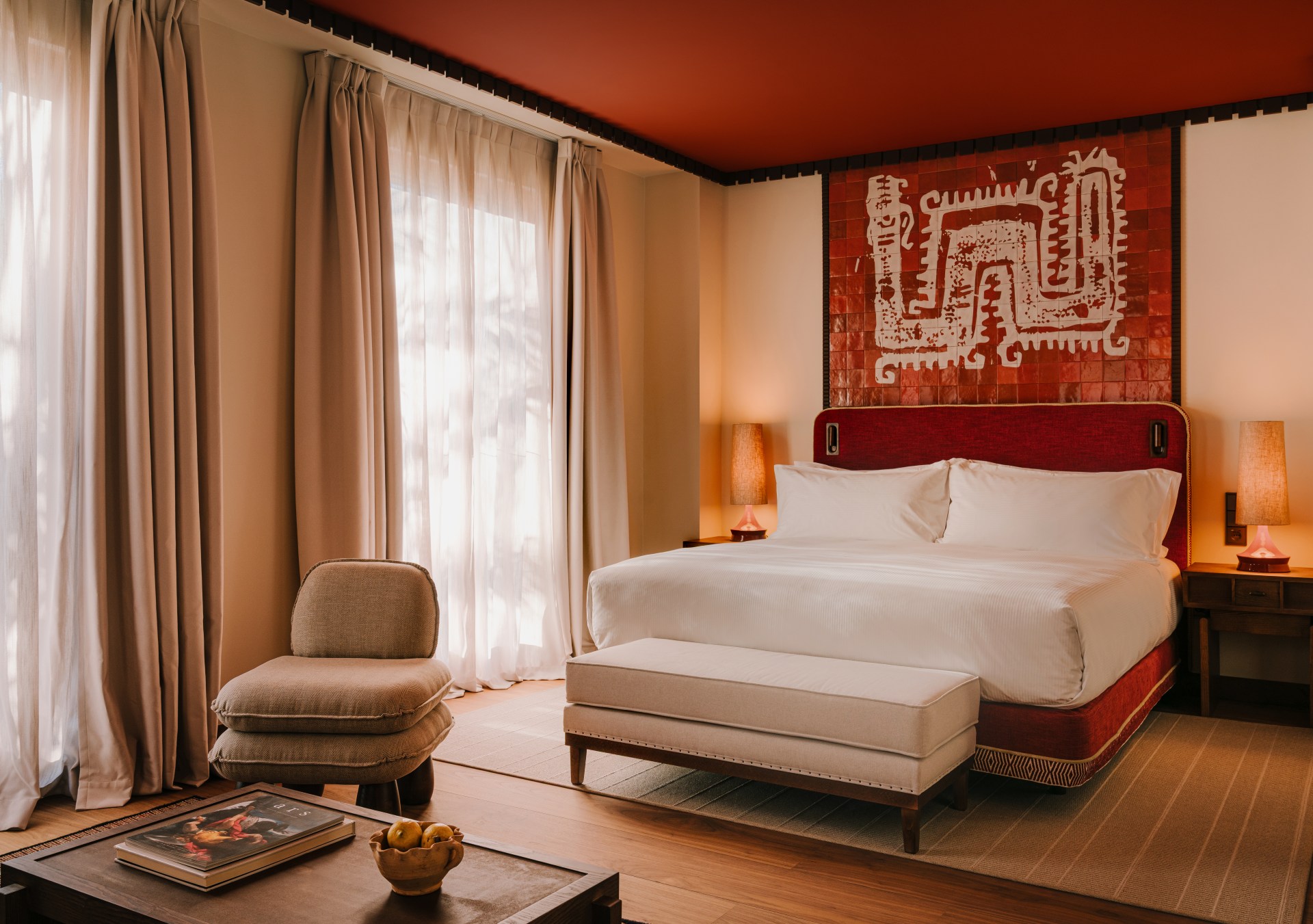 A bedroom with a bed, bench, and a seating area.
