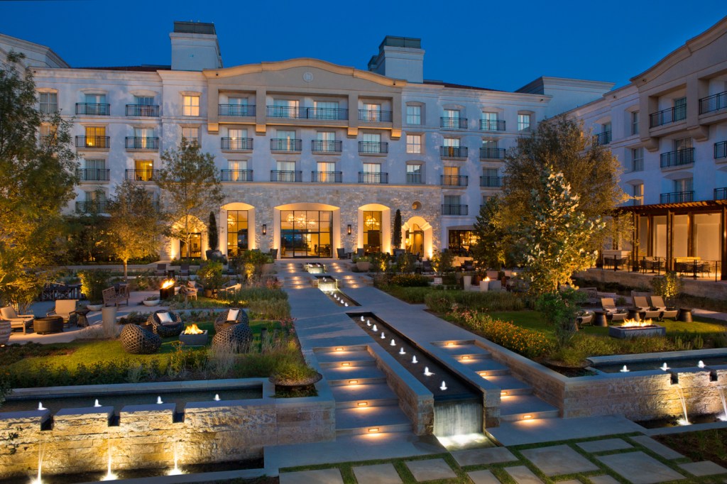 A plaza outside Signia by Hilton La Cantera Resort &amp; Spa in the evening with many seating areas gathered around gas fire pits