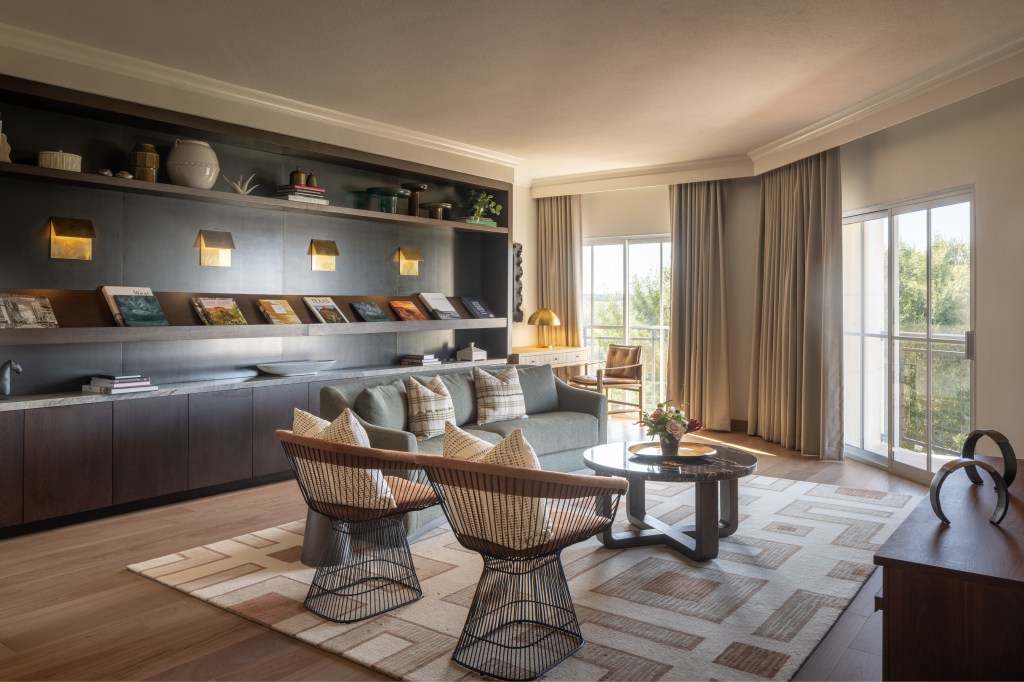 A seating area with a couch, two chairs, a coffee table in front of a bookcase.