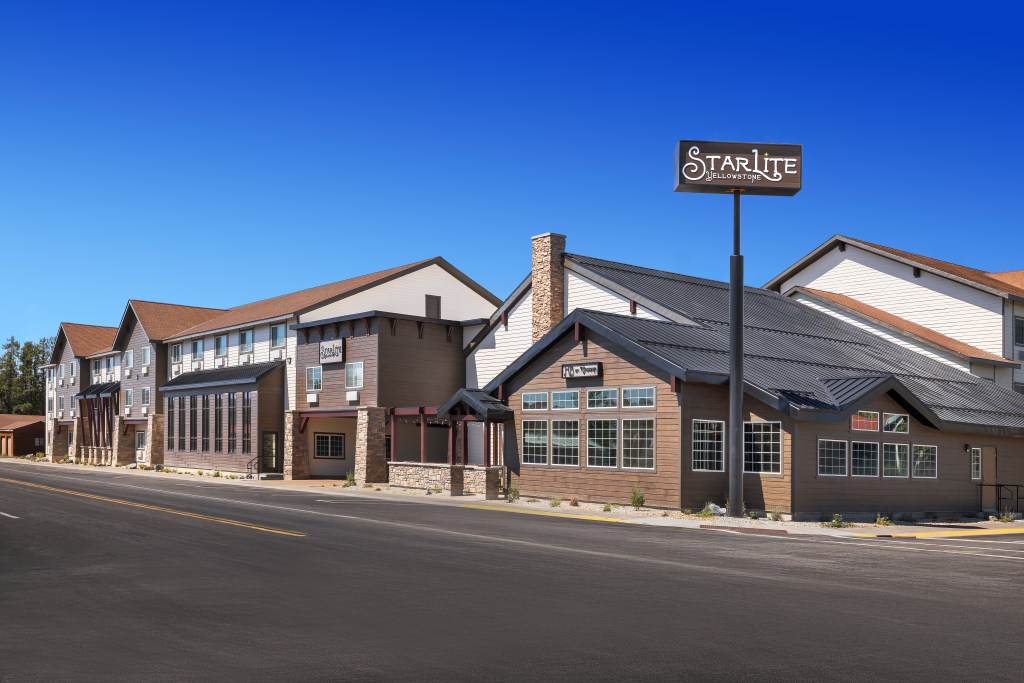 daytime exterior of Starlite Yellowstone, Tapestry Collection by Hilton - hotel with white and brown wood, black roof,