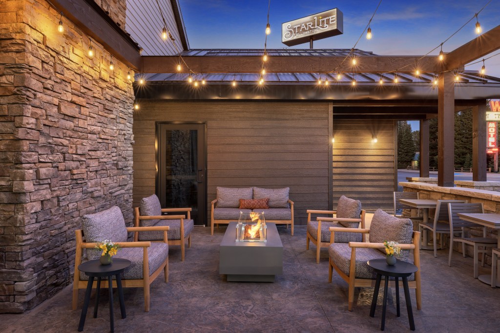 Firepit patio lit up at night with string lights at Starlite Yellowstone, Tapestry Collection by Hilton