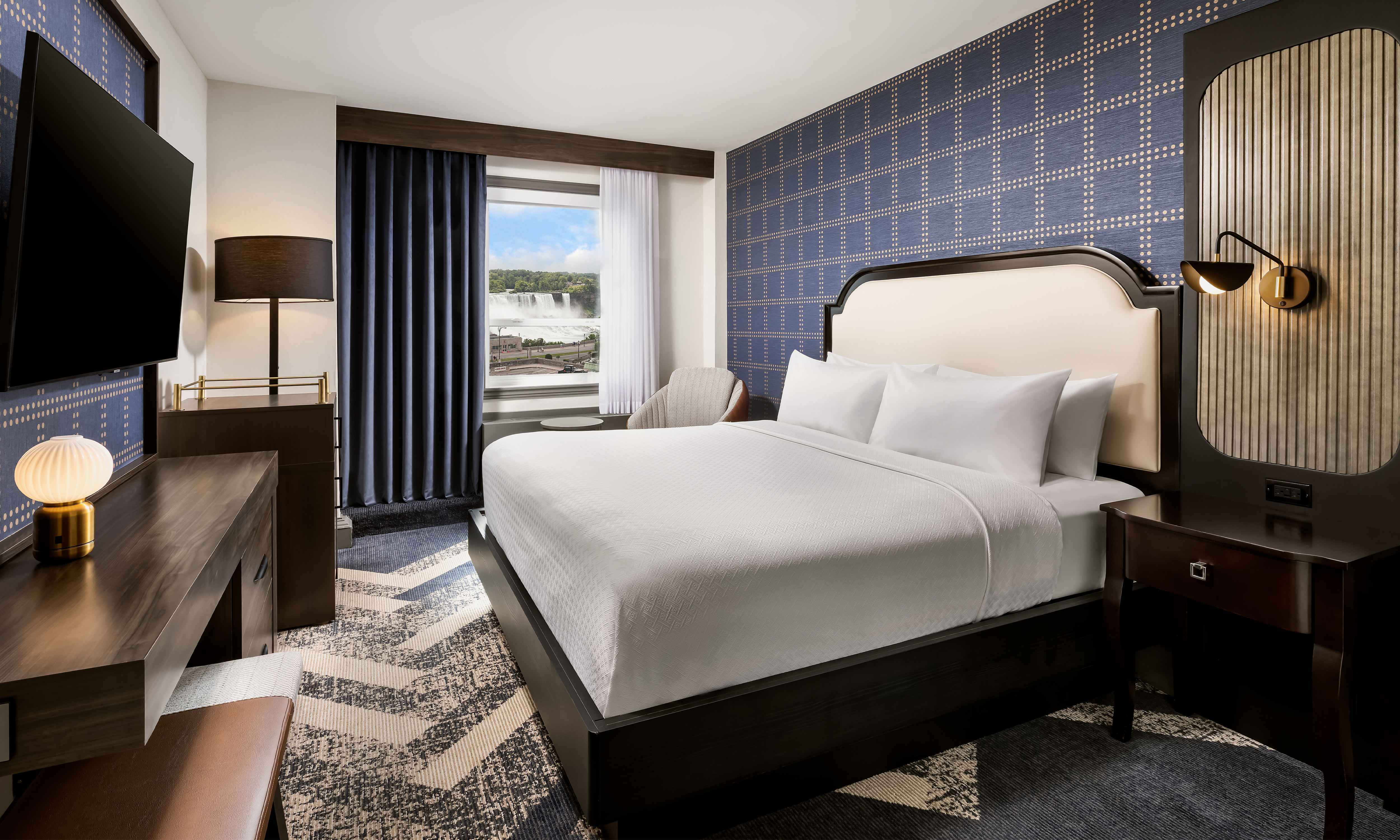 A bedroom with bed, tv, dresser, and chair.