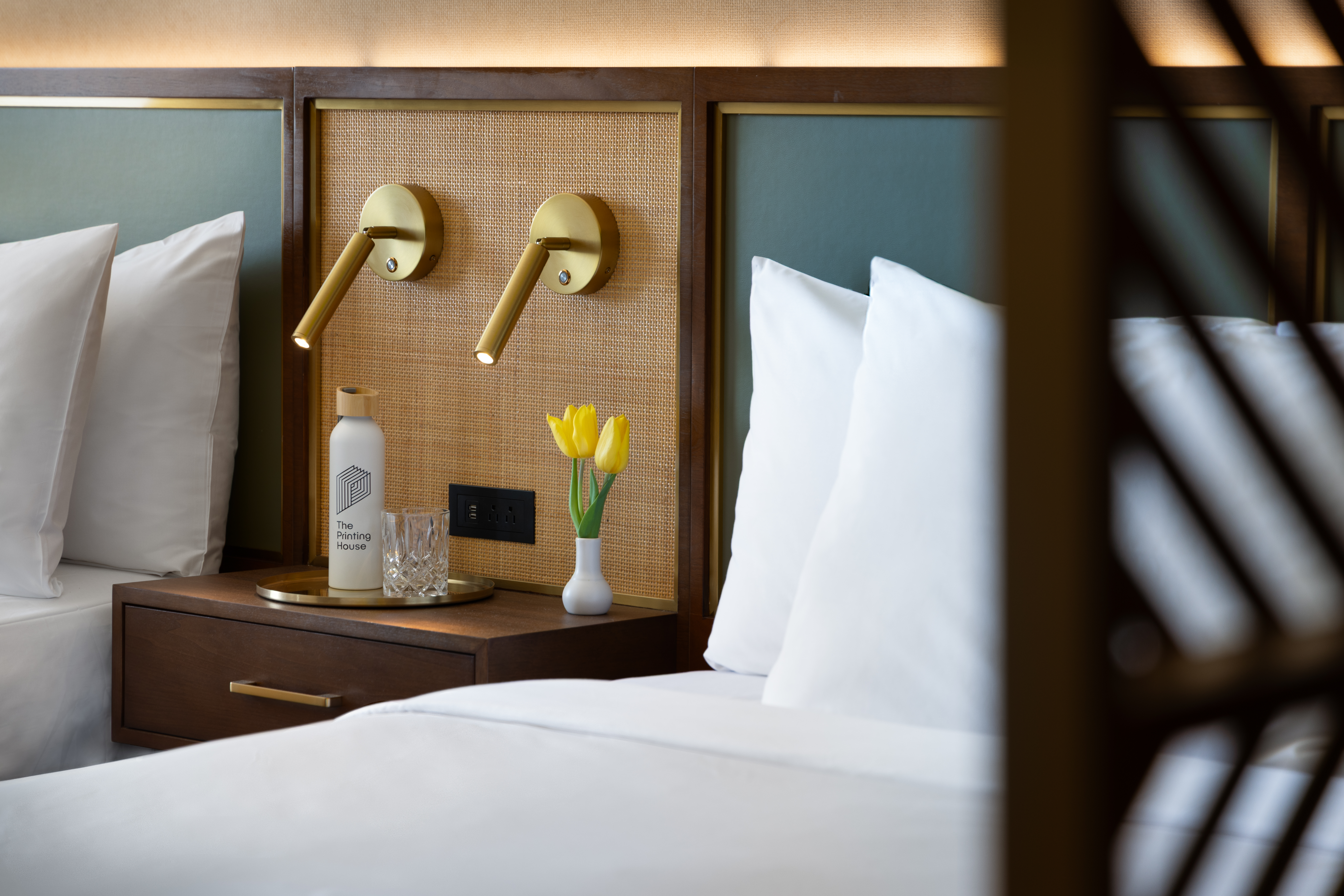 Details of the guest bed room featuring the nightstand and reading lights in between two queen beds