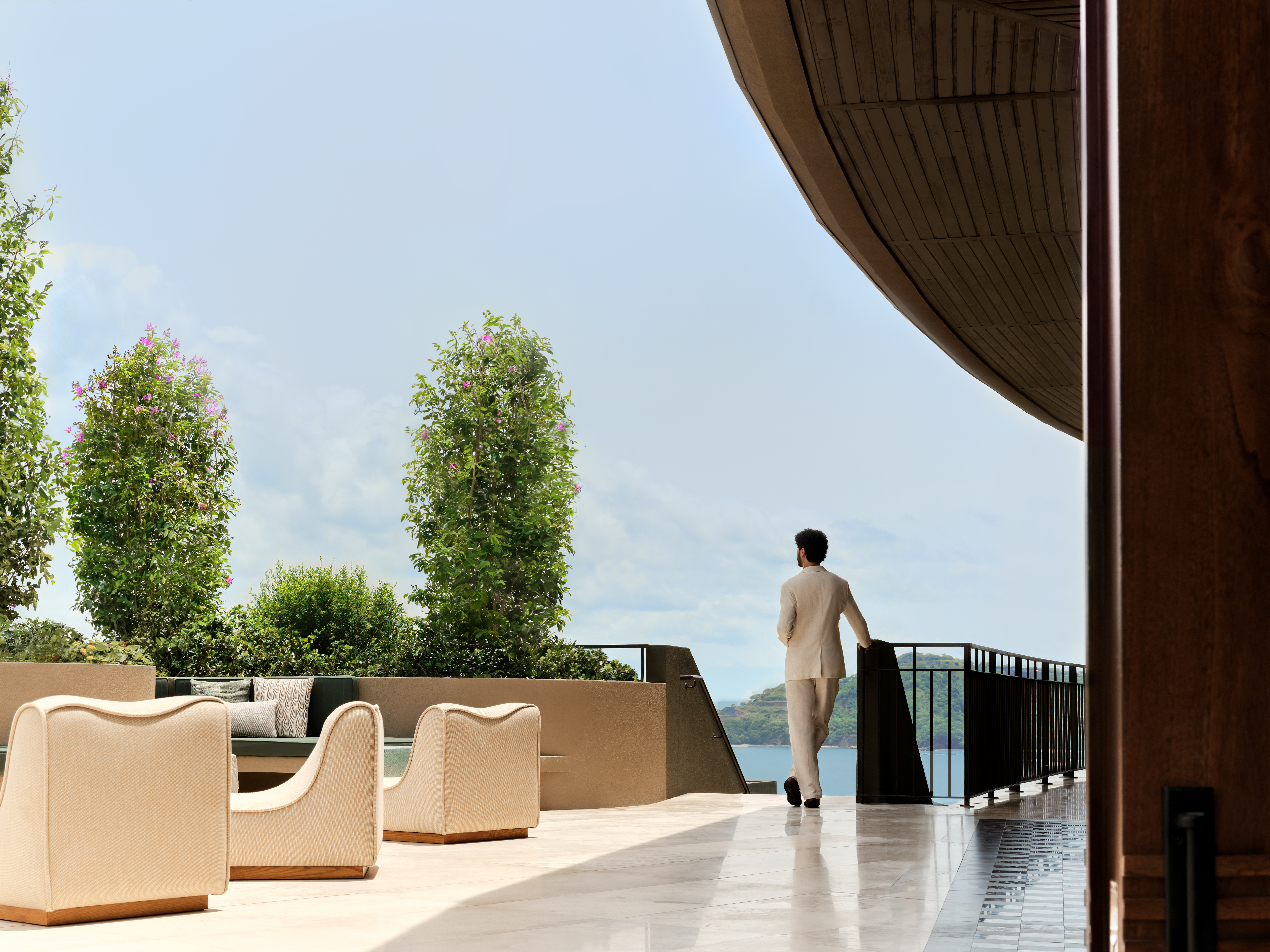 Waldorf Astoria Costa Rica Punta Cacique. man standing next to staircase overlooking the water and seating area
