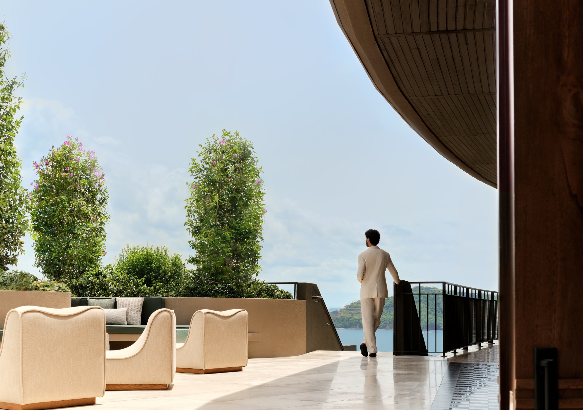 Waldorf Astoria Costa Rica Punta Cacique. man standing next to staircase overlooking the water and seating area