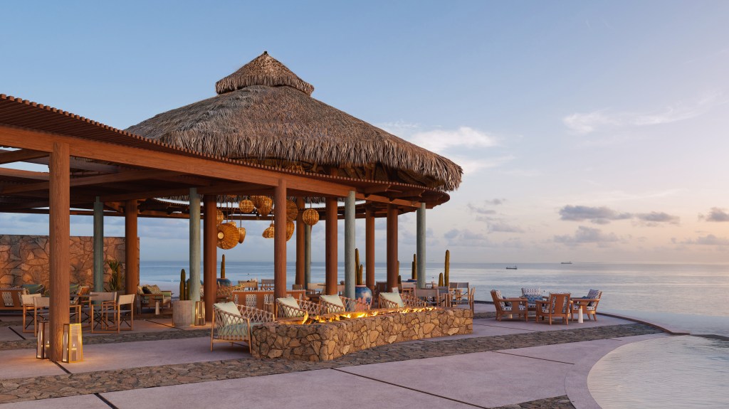 Waldorf Astoria Los Cabos Pedregal Beach Club outdoor seating area with fire pit and lantern lights along the beams of the building all overlooking the water