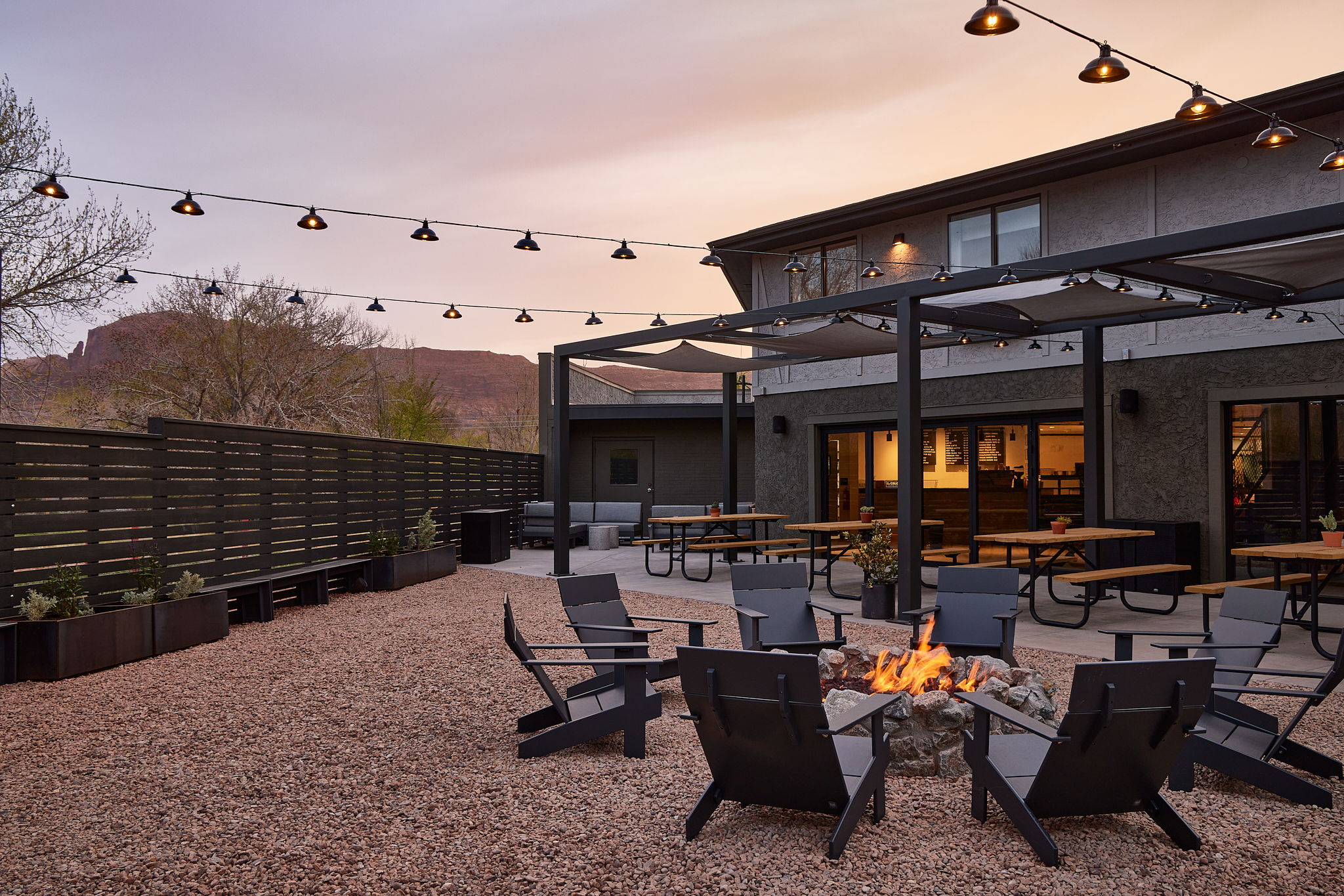 Chairs gathered around a firepit, with picnic tables and building in background