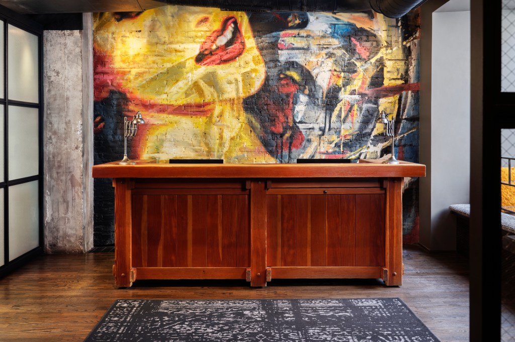 ACME Hotel Chicago - Front Desk, wooden front desk with colorful artwork behind it