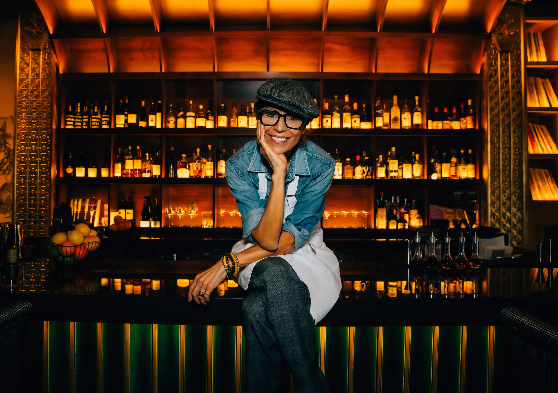 Dominique Crenn sitting in front of a bar, smiling at camera
